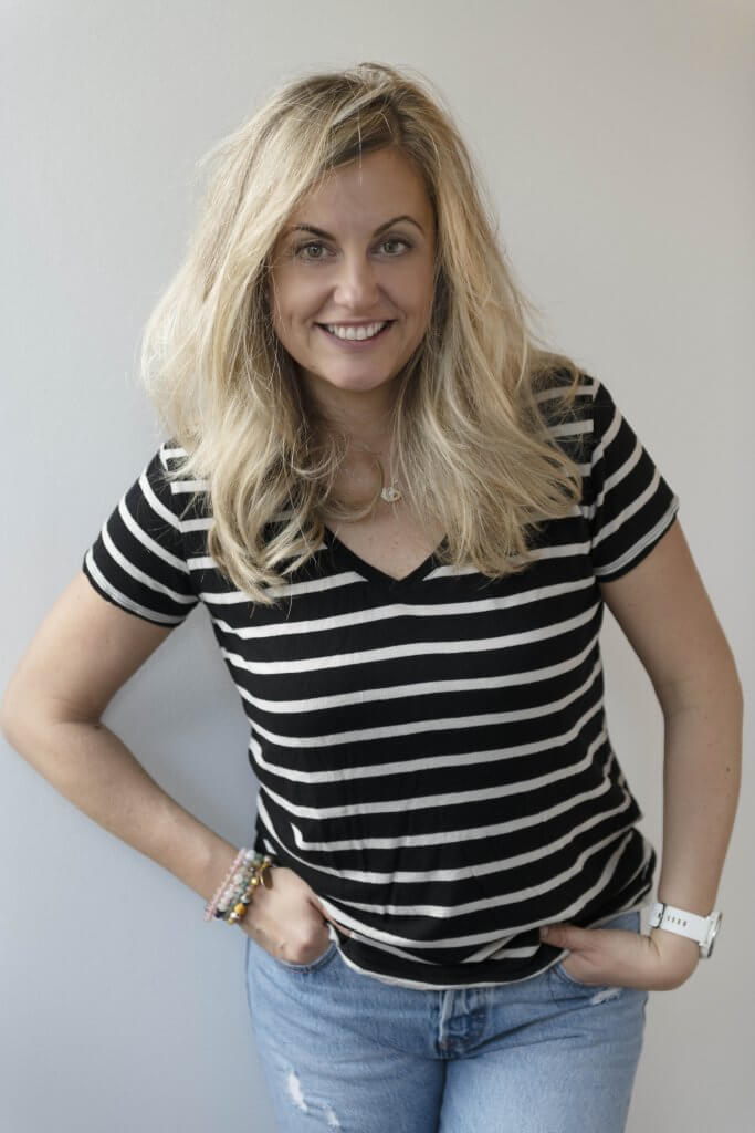 Woman standing against wall smiling